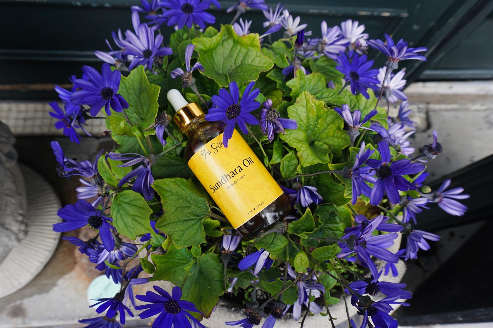 Sundhara Hair Oil resting among purple blooms